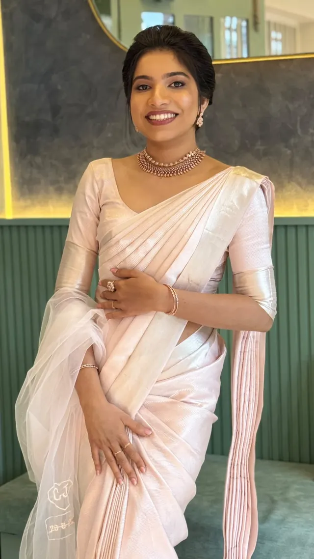 Bride in a pale pink Kerala saree with a softly sculpted updo and natural makeup