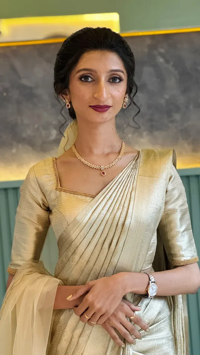 Bride in a gold Kerala saree with an elegant updo and soft berry makeup
