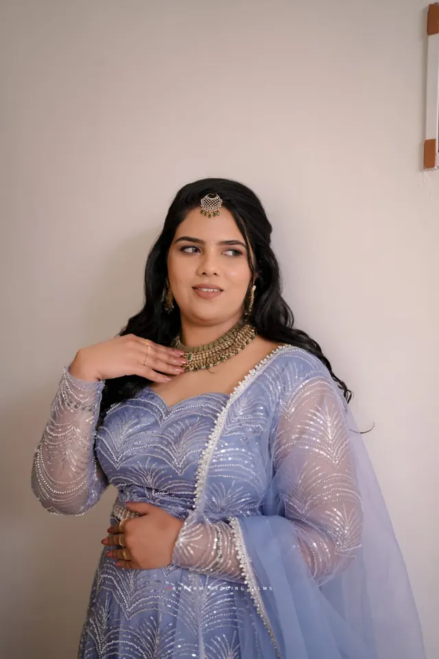 Bride in a lavender sequinned lehenga with maang tikka and green-stone necklace
