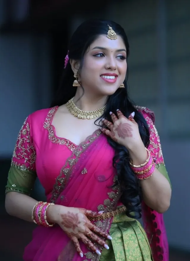 Bride in pink half saree with mehendi hands and gold jewellery