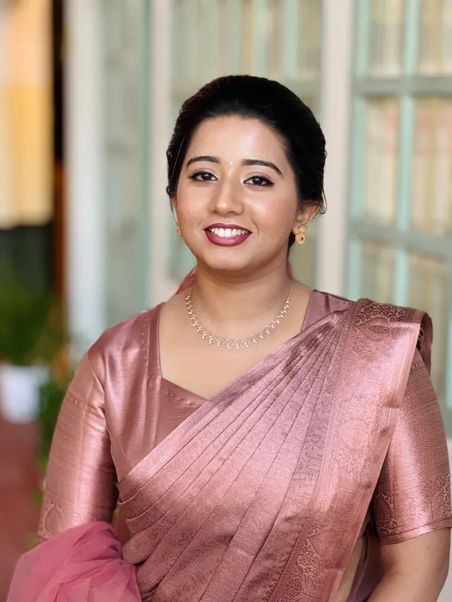 Bride in a rose silk saree with polished natural makeup and a classic updo