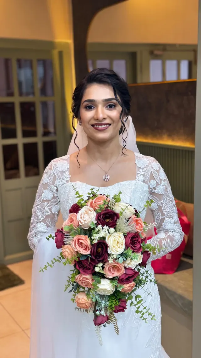 Christian bride in a white lace gown holding a cascading burgundy and blush bouquet