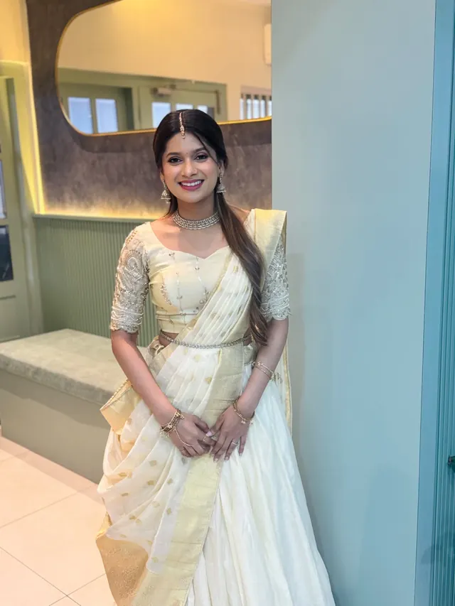 Bride in an ivory Kerala saree with side-swept hair and soft bridal makeup