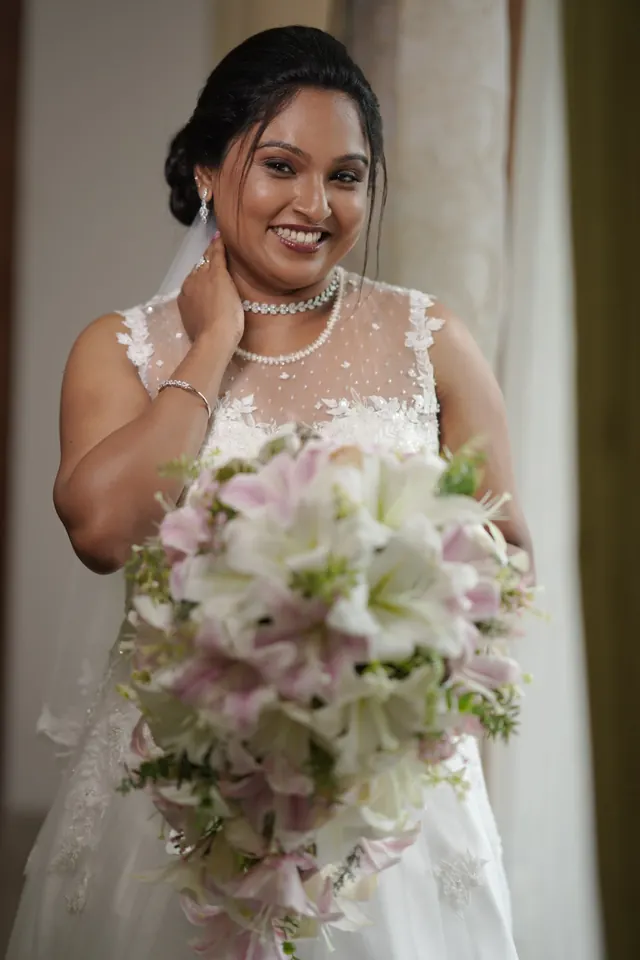 Christian bride in a white lace gown holding a white and pink lily bouquet