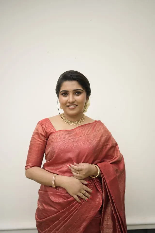 Bride in a rose-red Kanjivaram saree with gold choker and jasmine in her hair